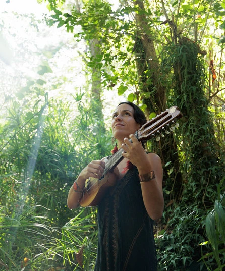 Loli Cósmica con su guitarra entre la vegetación